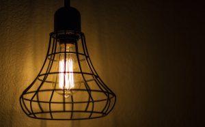 Close-up of a vintage Edison bulb inside a wire cage fixture casting warm light.