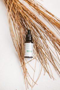 High-quality CBD oil bottle on a white background with natural twigs, perfect for product promotions.