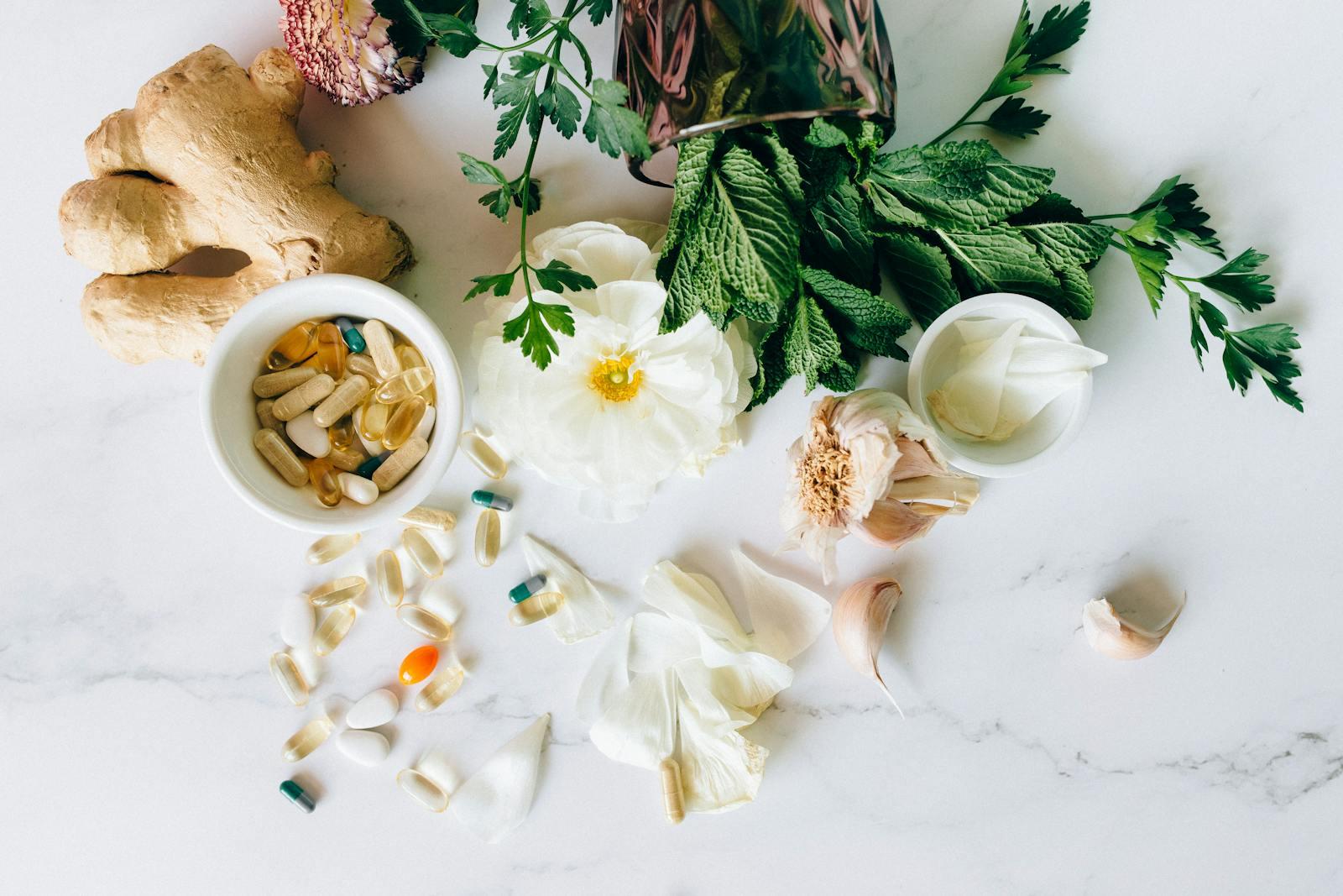 A flatlay of herbal supplements with fresh ginger, garlic, and leaves.