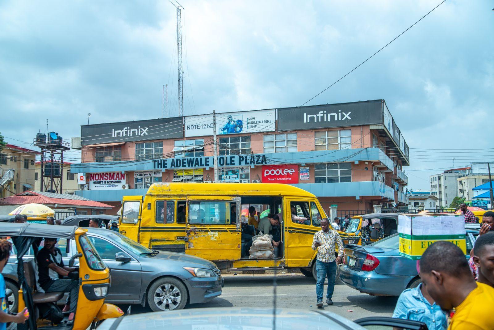 Vibrant urban life in Lagos with traffic and pedestrians by The Adewale Kola Plaza.