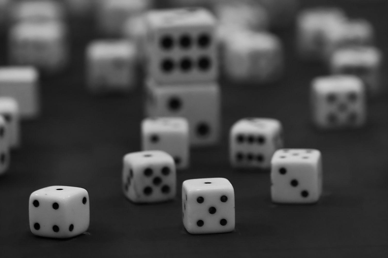 Black and white photo of scattered dice, focusing on one die in sharp detail.