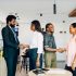 Four adults engage in a professional handshake at a cafe in Lagos, Nigeria, showcasing teamwork and collaboration.