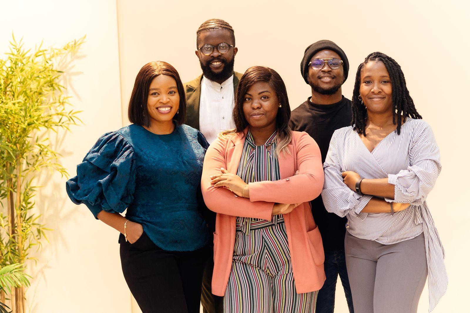 A diverse group of business professionals smiling confidently indoors.