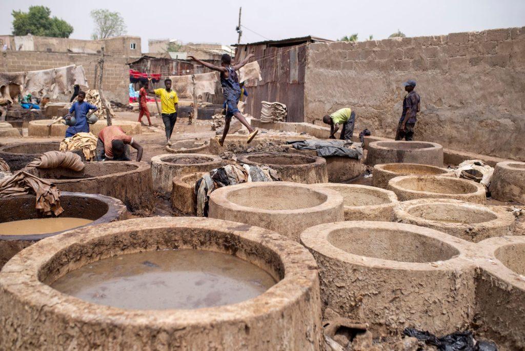 Workers using traditional methods in large clay tanning vats for leather processing.