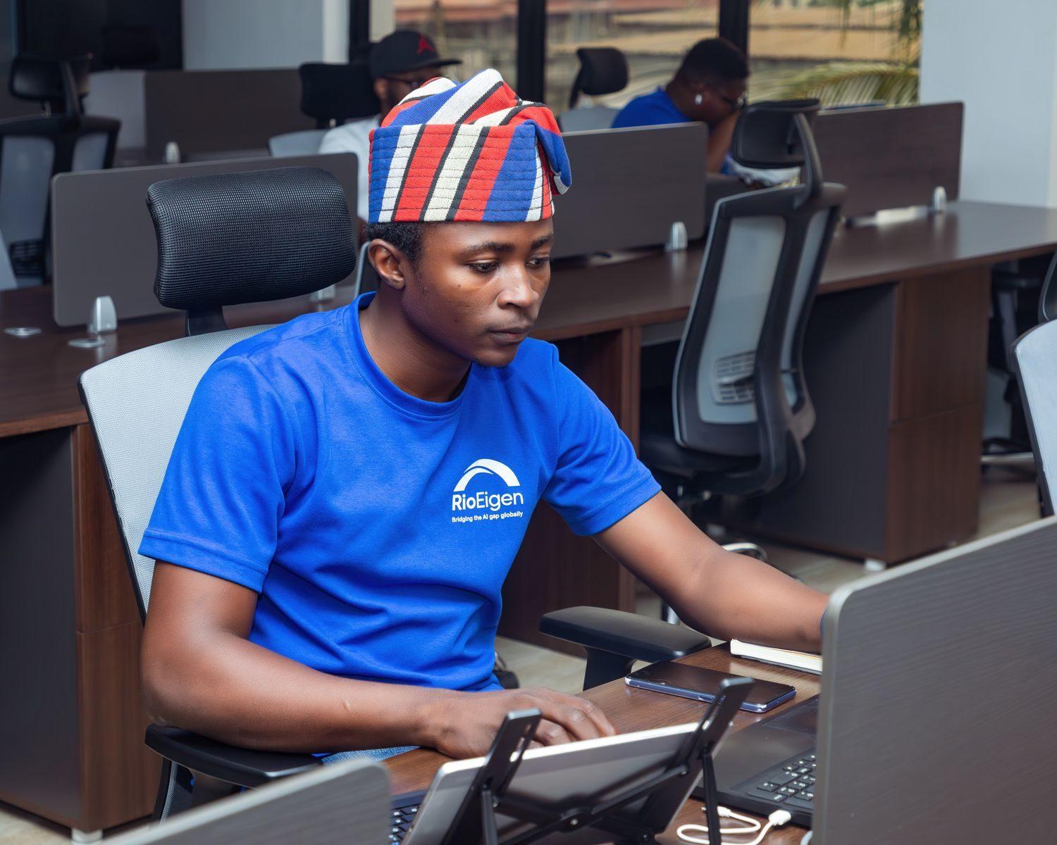 Focused man in traditional hat working at computer in a modern office environment.