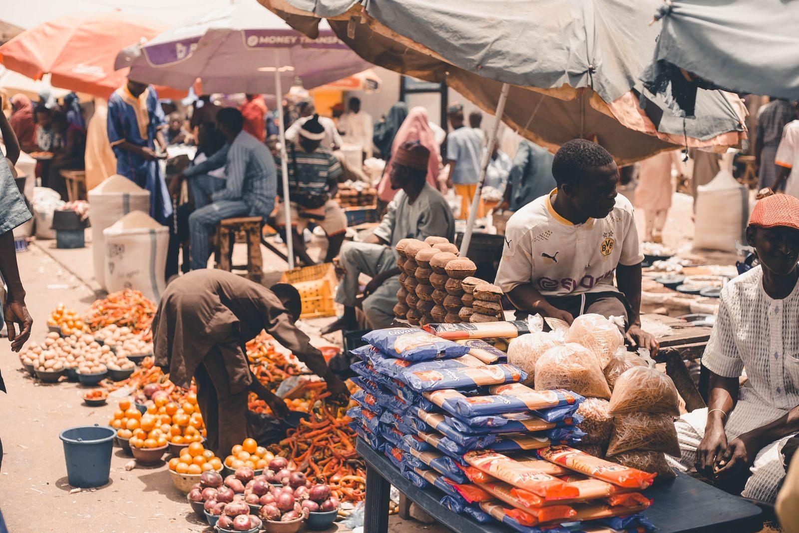 Lively market scene showcasing fresh produce and vendors under colorful umbrellas, capturing the essence of local trade.