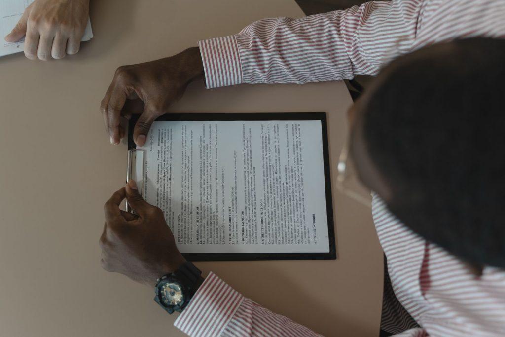 Photo by Tima Miroshnichenko A close-up, overhead view of an individual holding a document during a business meeting.
