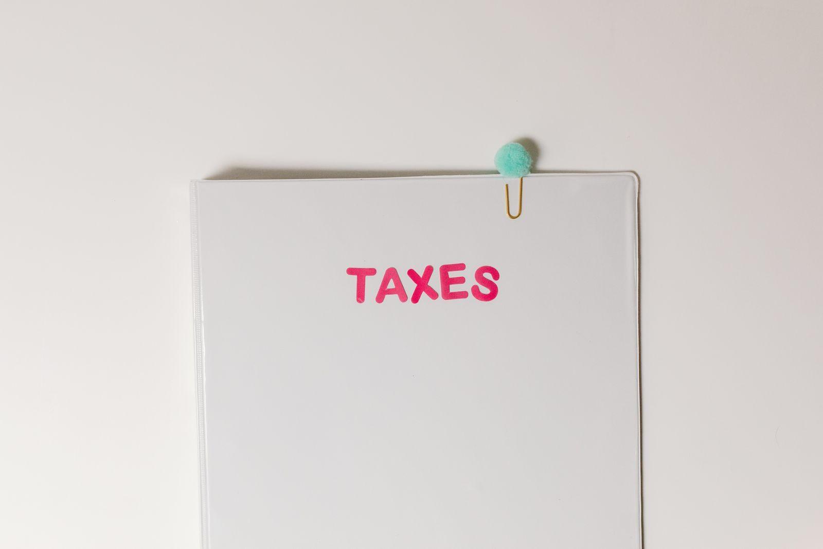 Close-up of a tax file with a pink 'TAXES' label and a paperclip, offering copy space and a conceptual minimalist design.
