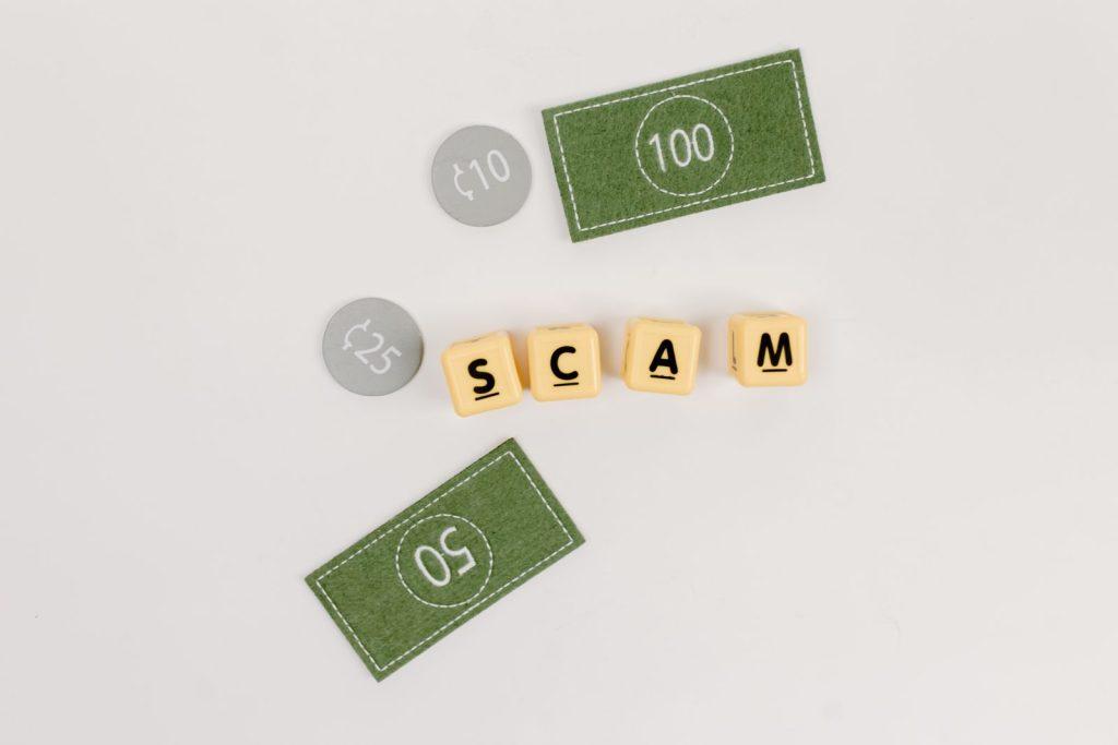 Flat lay of fake currency and scam letters on a gray surface representing financial deception.