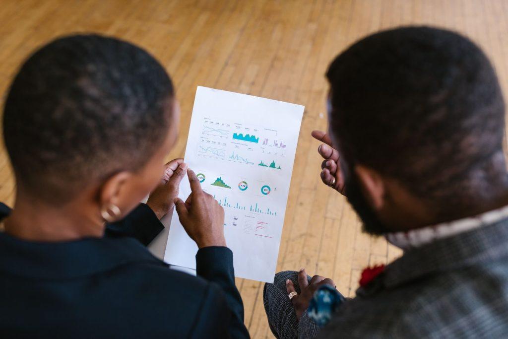 Two business colleagues examining a document with charts in an office setting.