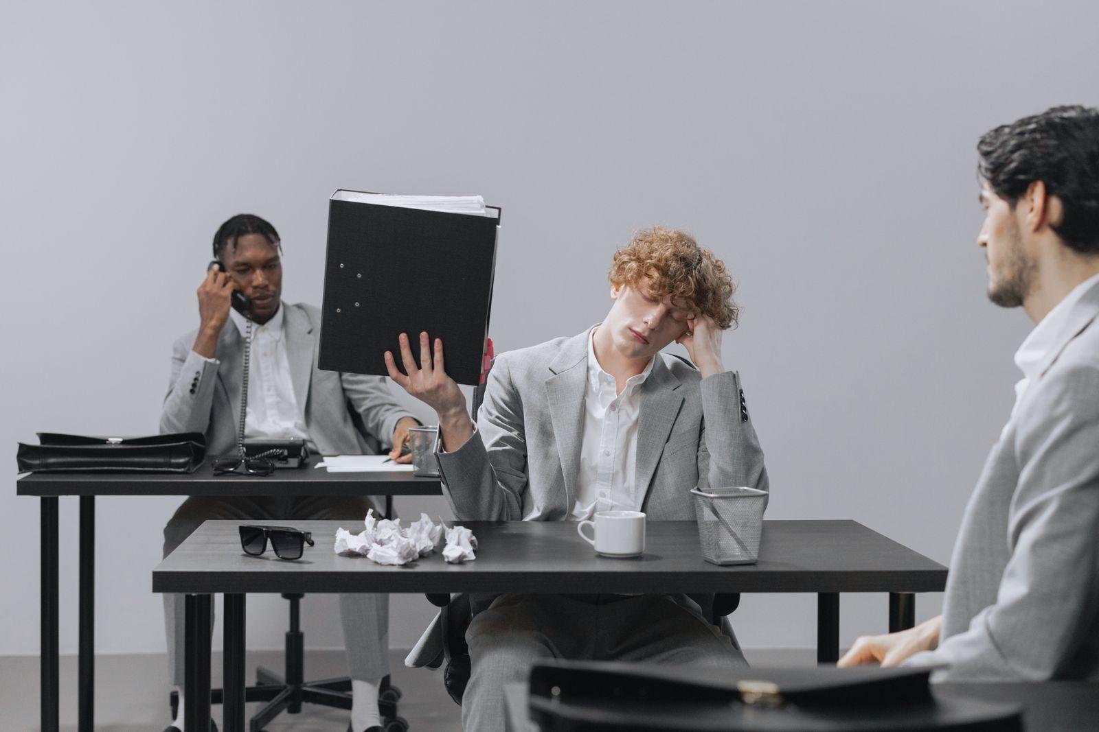 Coworkers in an office dealing with stress and paperwork fatigue.