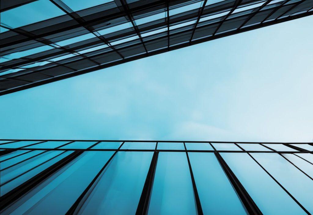 Striking low-angle shot of glass buildings against a clear blue sky, showcasing modern architectural design.