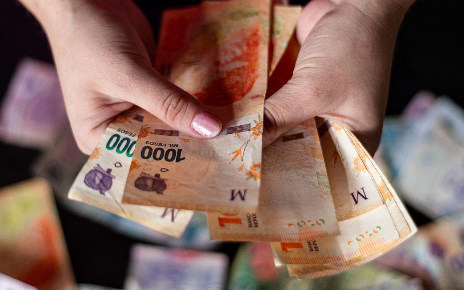Detailed view of hands holding Argentine peso banknotes, symbolizing financial concepts.
