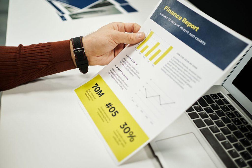 Photo by Jack Sparrow Person analyzing finance report with graphs at desk, ideal for business concepts.
