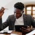 Confident businessman working on a tablet with documents in an office setting.