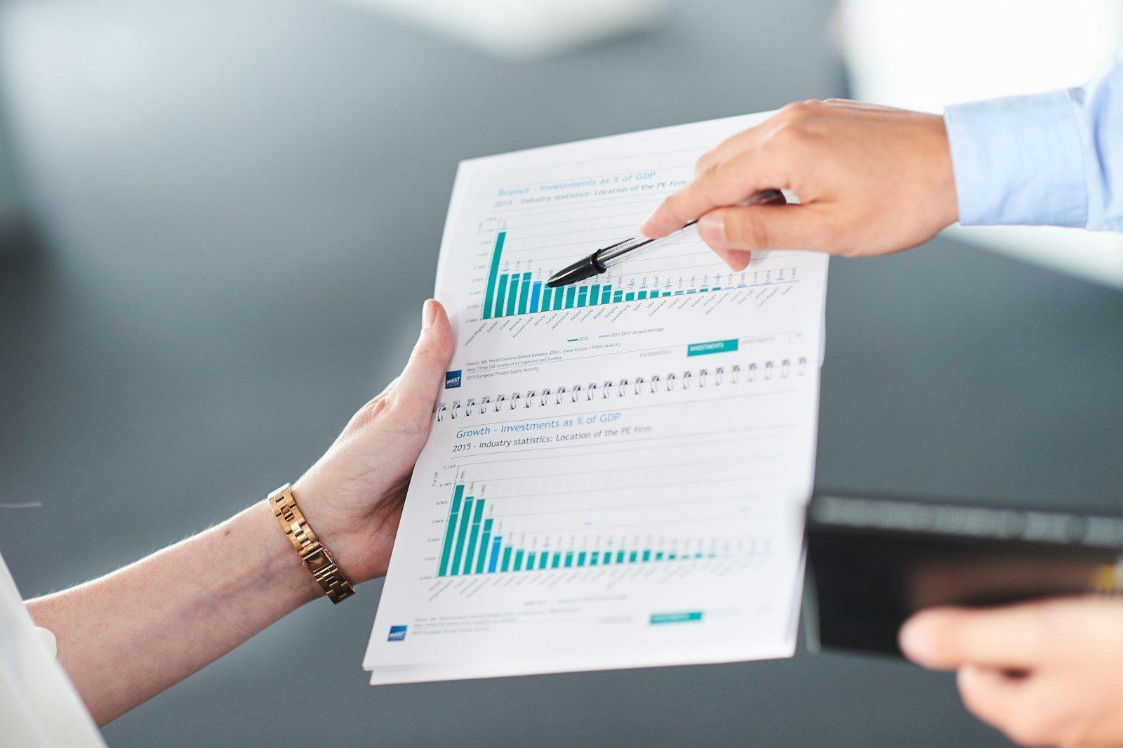 Two people analyzing a document with green bar charts