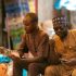 Men interacting and counted money at a market in Tudun Wada, Nigeria.