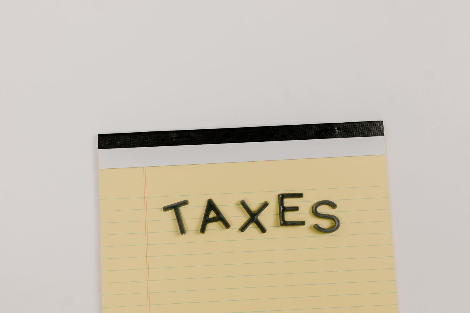 A flat lay of the word 'TAXES' on a yellow notepad, ideal for financial content.