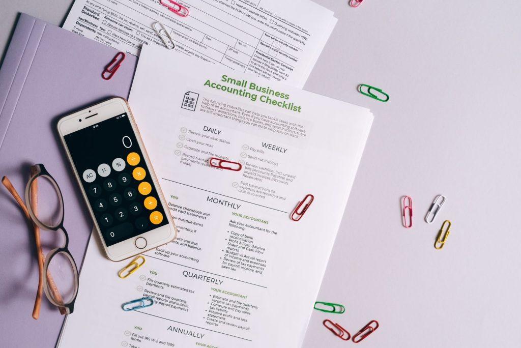 Photo by Leeloo The First Top view of accounting essentials including smartphone, eyeglasses, and paperwork.