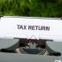 a close up of a typewriter with a tax return sign on it