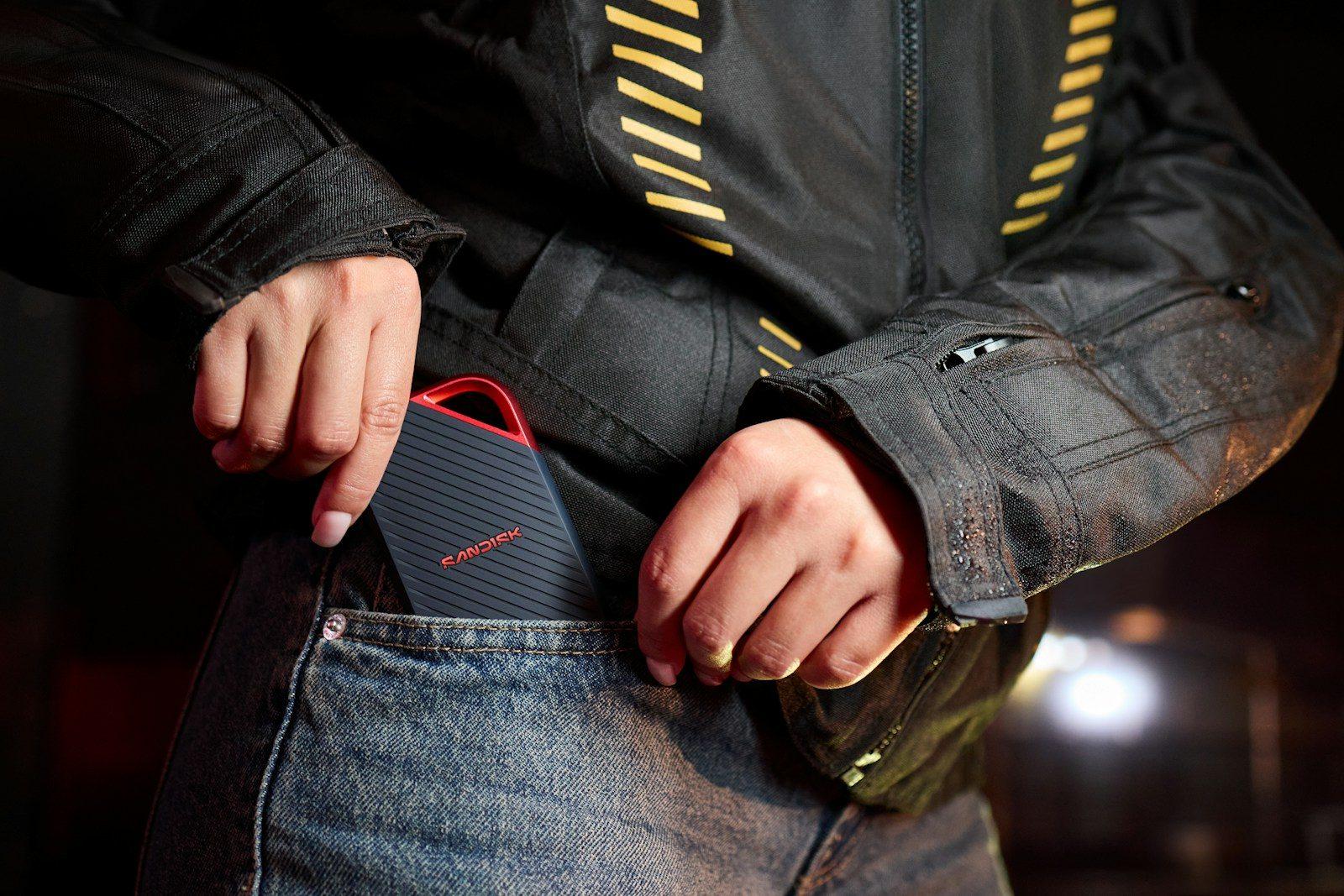 A person puts a portable speaker into a jeans pocket